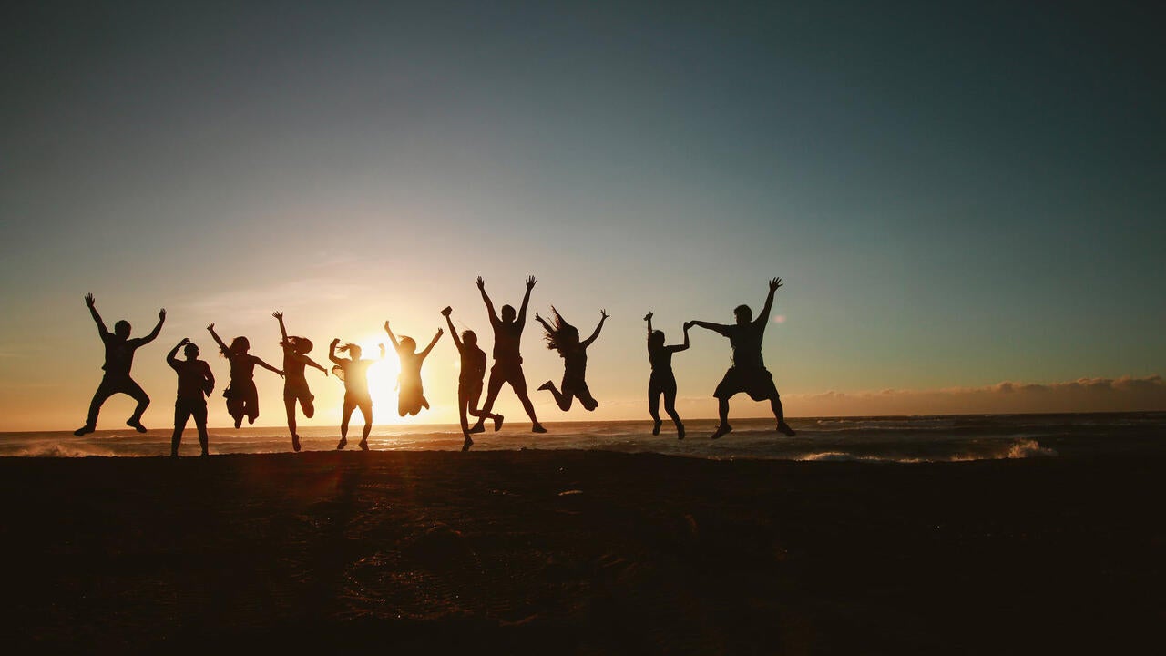 Line of people jumping over horizon towards sun