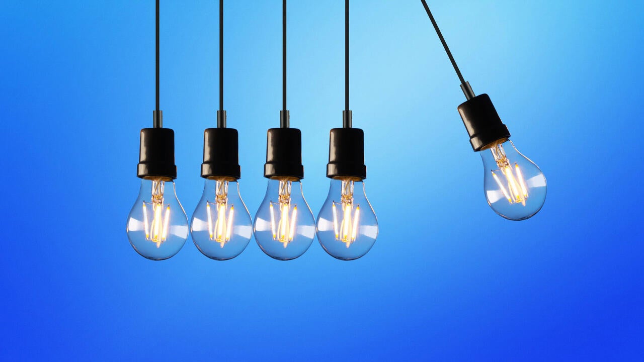 Four hanging light bulbs with one swinging towards them on the right