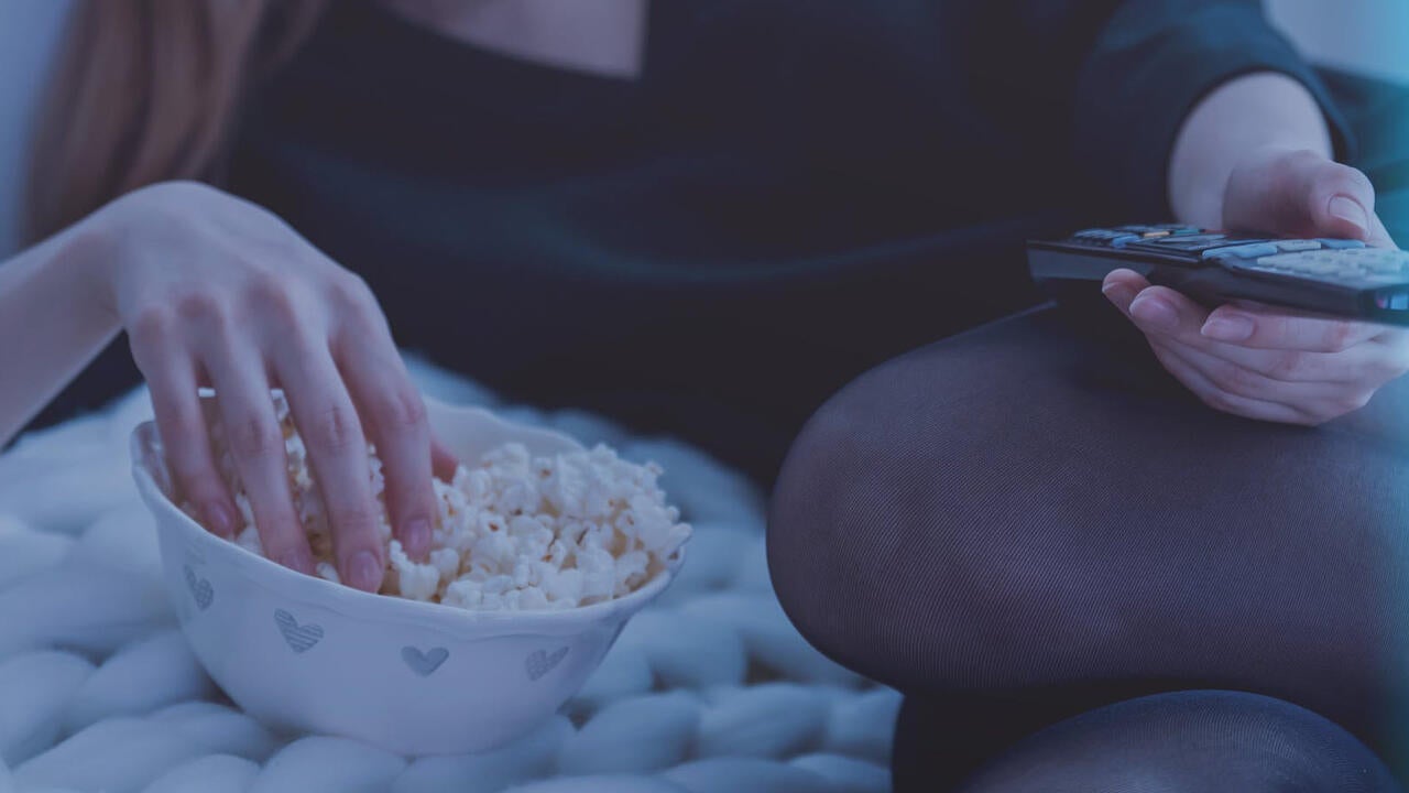 Person on bed with remote in hand watching TV