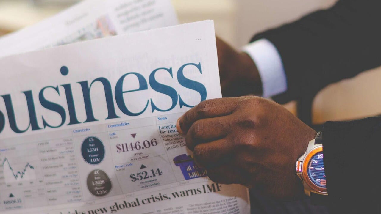 Man holding Newspaper with business in the front 