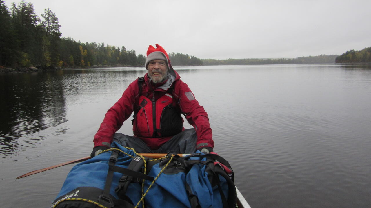 Murray smiles from the back of a canoe, paddle in hand