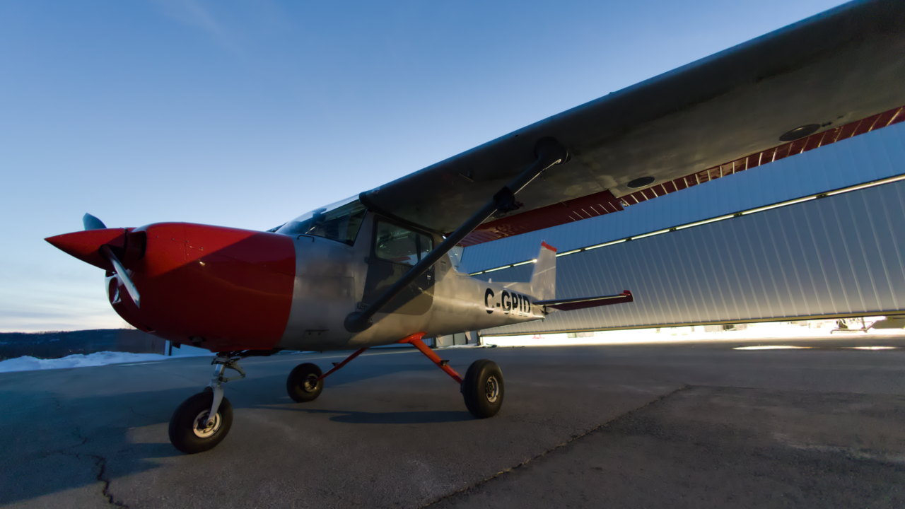 Small red and white plane parked at hanger