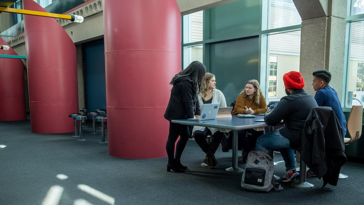 A group of students gather around a table in the Davis Centre