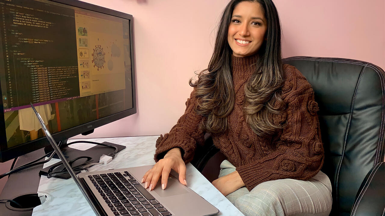 Sara Ibrahim sitting at her computer, looking at the children's story