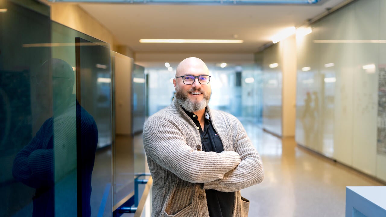 Man in glasses smiling with arms folded