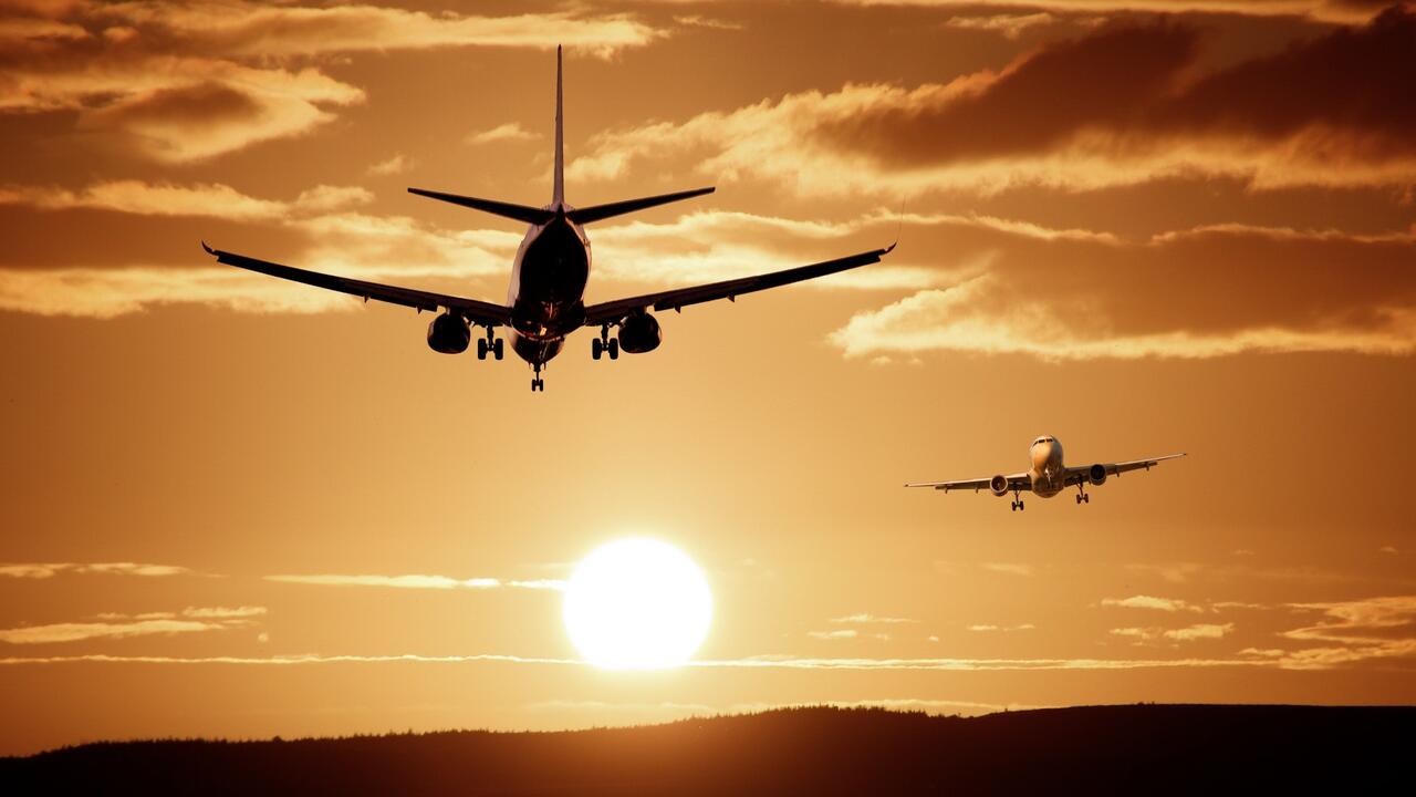 Two planes flying into orange sunset