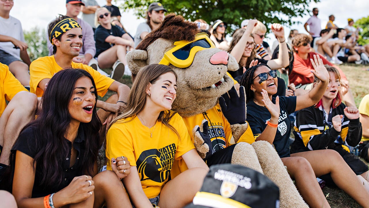 King Warrior sits with students at Black and Gold Day