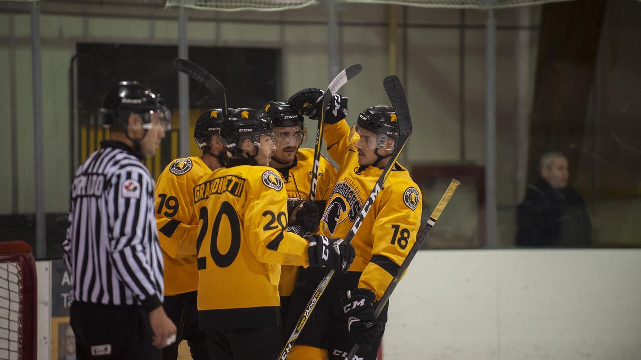 Men's hockey players gather on the ice