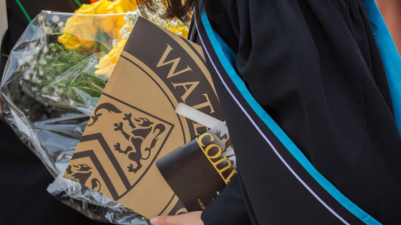 Student holding their diploma and flowers
