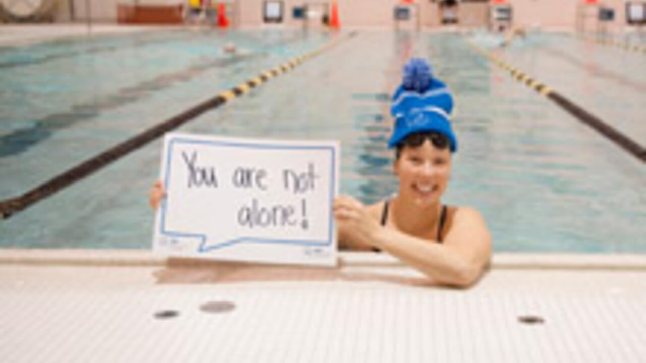 Waterloo varsity swimmer holding sign that reads 