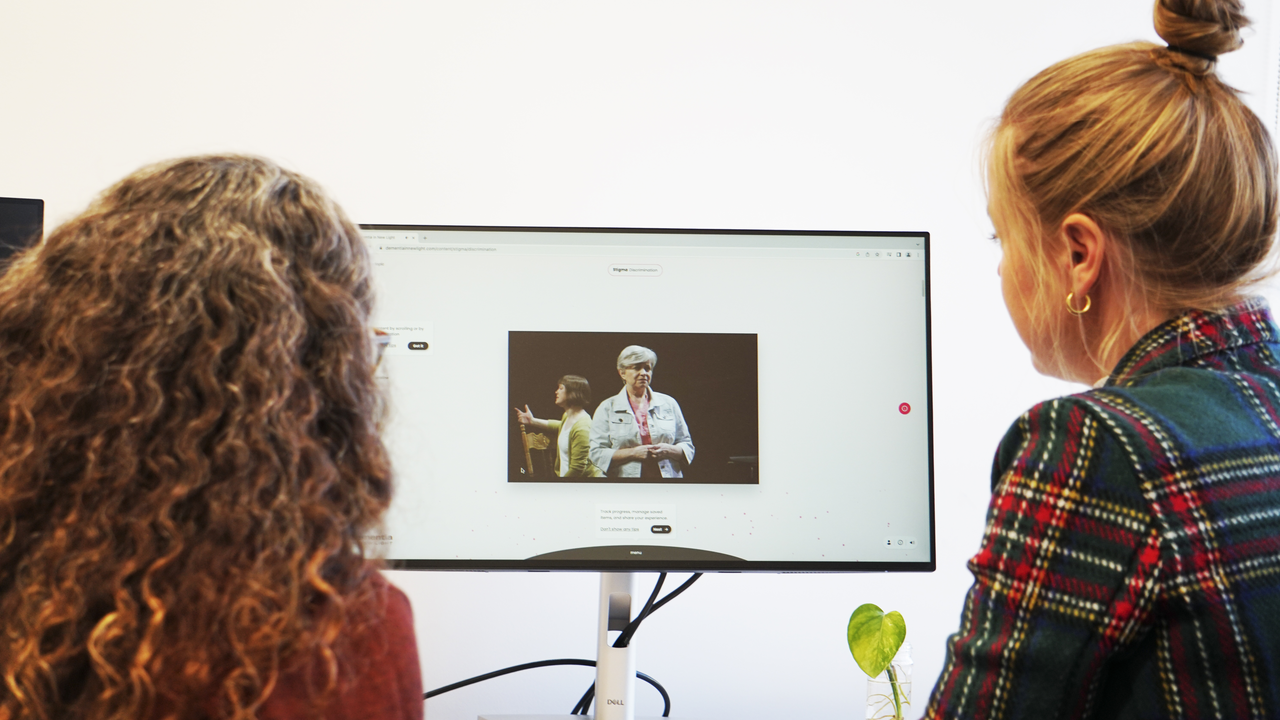 Two women watching the play on a screen