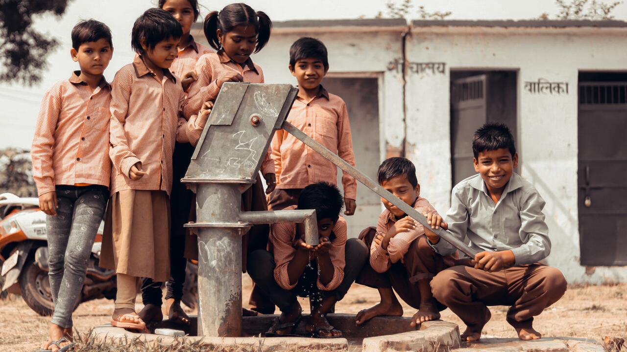 Indian children beside a water pump
