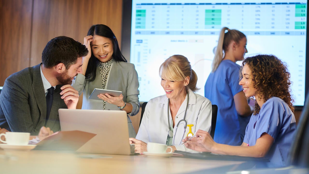 Medical professionals and hospital executives meeting with a giant screen in the background