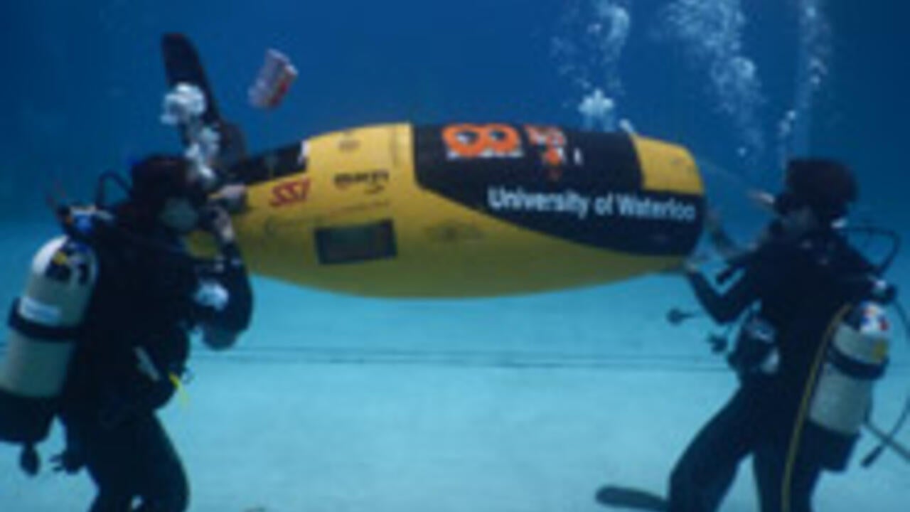 Members of the WatSub team race their submarine, AMY
