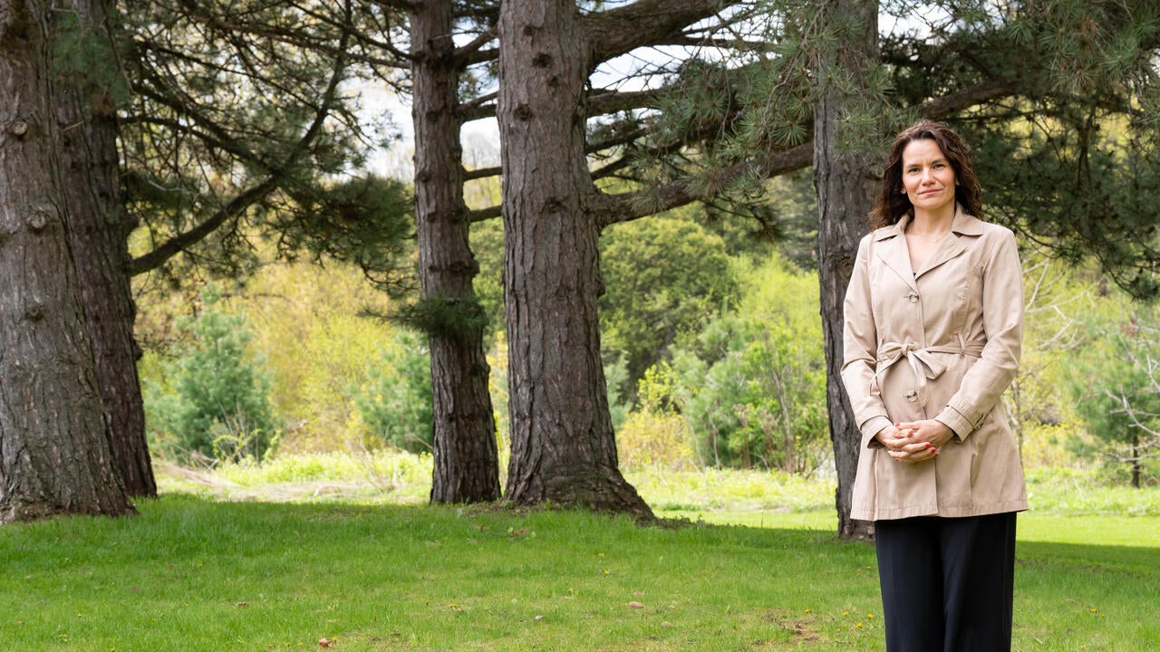 Anabela Bonada stands amongst trees on a partly cloudy day