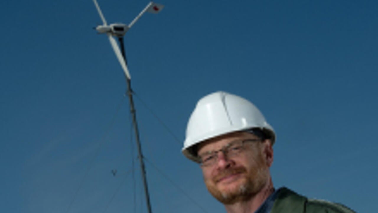 David Johnson standing in front of wind turbine