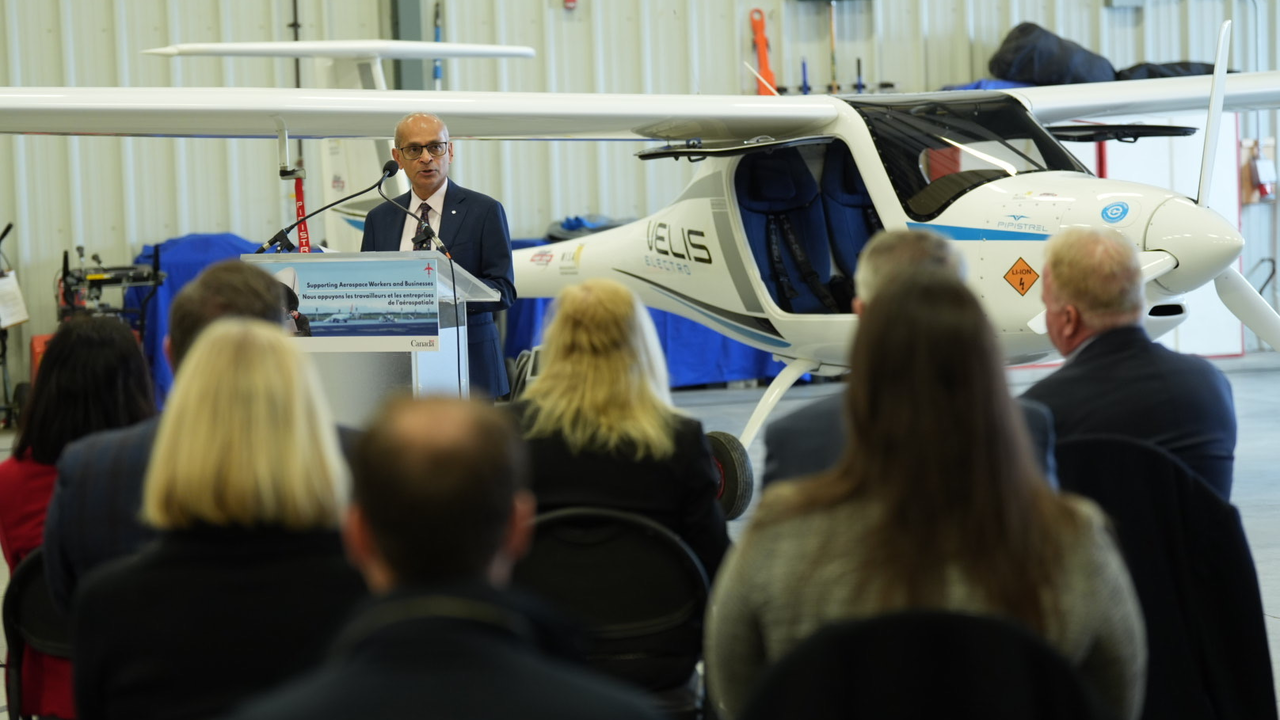 Waterloo president and vice-chancellor Dr. Vivek Goel speaking at an event with a plane in the background