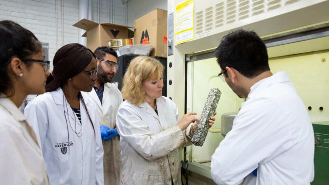 Group of researchers and senior researcher explaining an object
