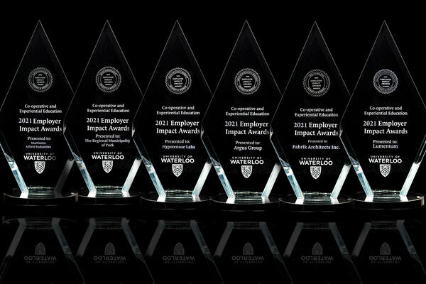 six glass awards lined up on a black table