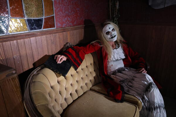 Meghan Snyder wearing a Halloween costume sitting on an antique couch inside one of Snyder's Farm's haunted houses