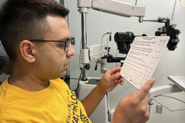 University of Waterloo Indigenous student, Jeremiah Hyslop, reading text on a standardized eye exam card