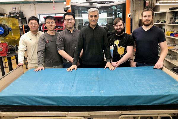 Researchers pose with a robotic bed they are using to develop an autonomous mobility system for hospitals.