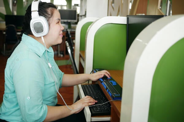 A blind student using a Braille keyboard and headphones for education