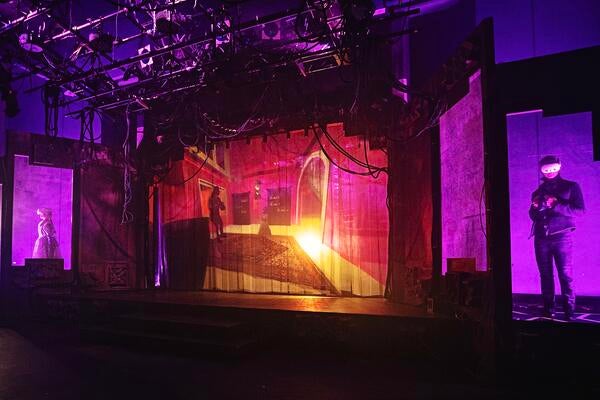 Stage with actors in VR headsets and screen showing their avatars