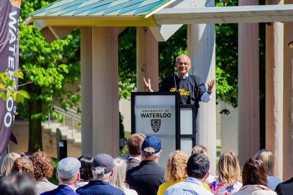 President Vivek Goel addresses a crowd from a podium outside the Indigenous Gathering space on campus