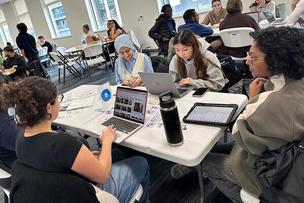 Students around a table with others milling in the backg