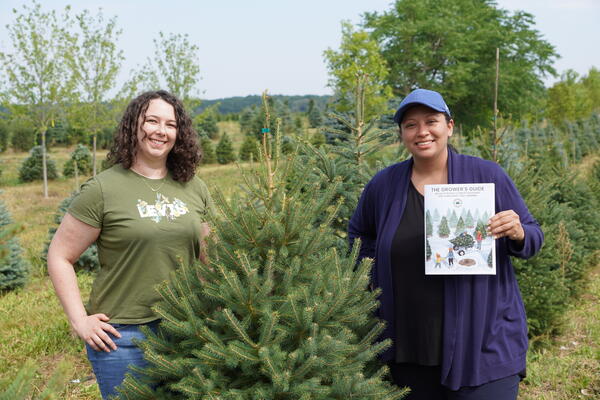 Two women standing beside a chirstmas tree. 