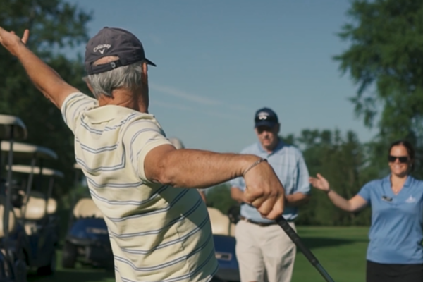 Older man celebrating with others on a golf course