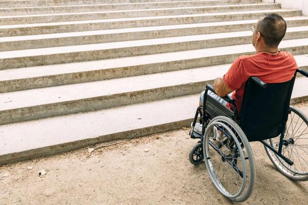 Person in a wheelchair at the bottom of a set of stairs