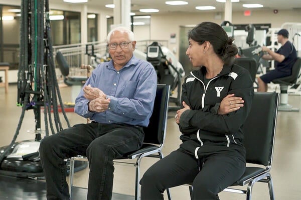 Older person and trainer in gym setting
