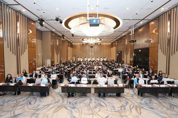 A large group of researchers sitting together at desks in a meeting room