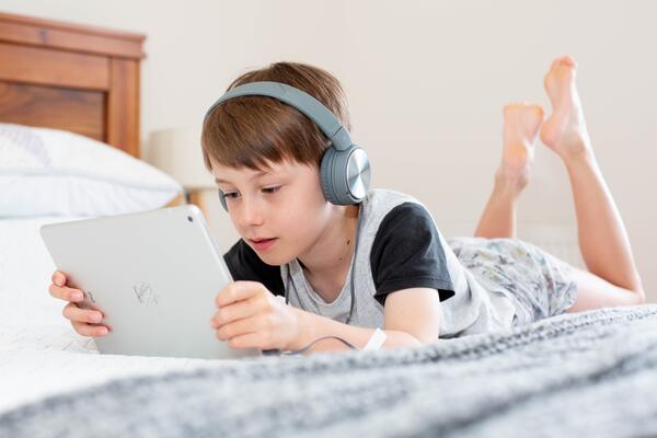 child wearing headphones and watching a tablet