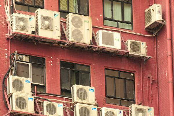 Multiple building cooling fans on the outside of a red building