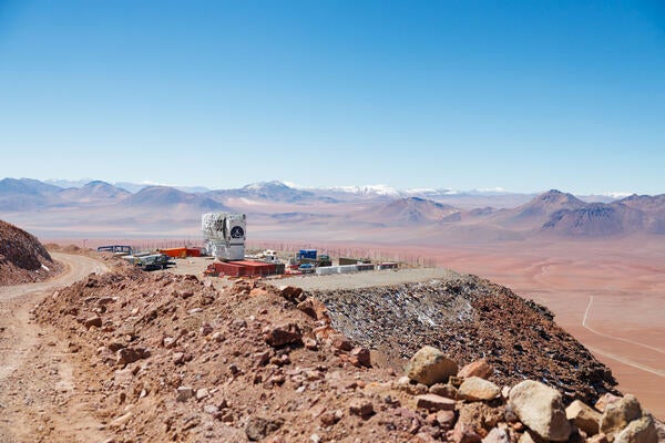 observatory on a cliff edge overlooking an open desert with mountains