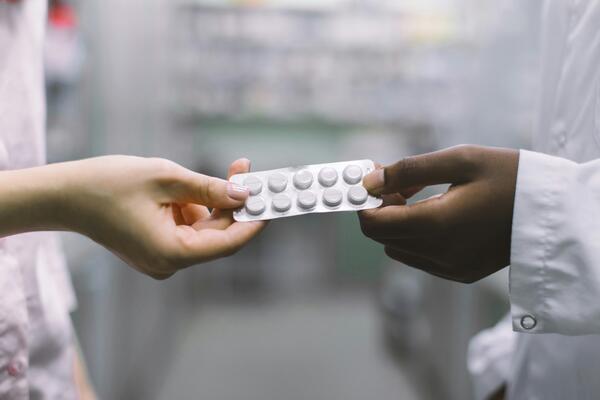 A pharmacist handing pills to a customer