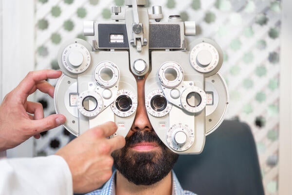 Optometrist doing sight testing for male patient in clinic