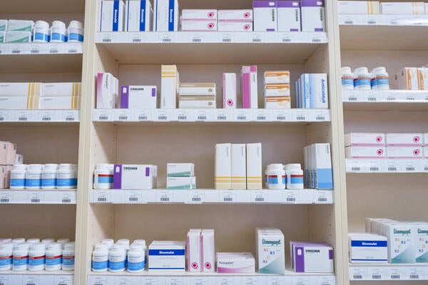 Shelves stacked with medicine bottles and boxes in pharmacy.