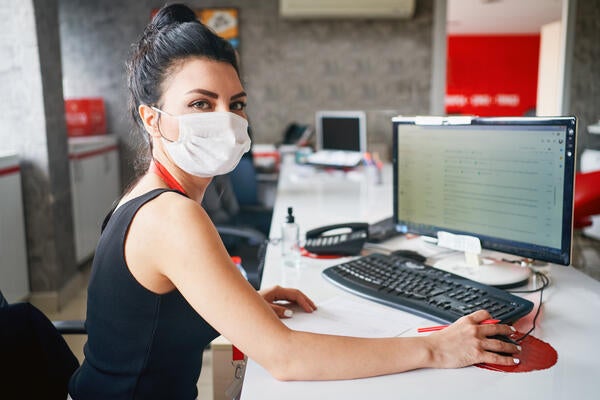 Woman wearing face mask in the office during COVID-19 pandemic 