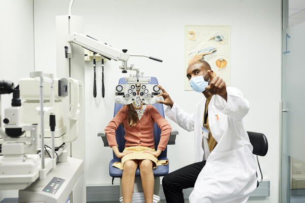 Ophthalmologist gesturing to girl in hospital