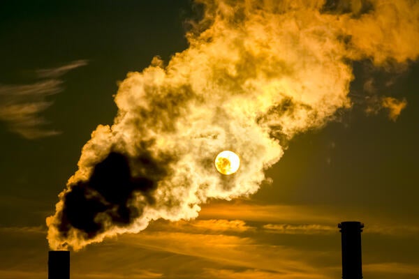 An image of smokestacks emitting smoke during a sunset