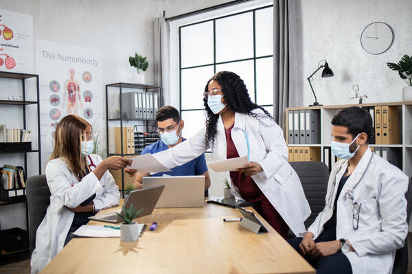 Doctors in protective masks with gadgets co-working at office