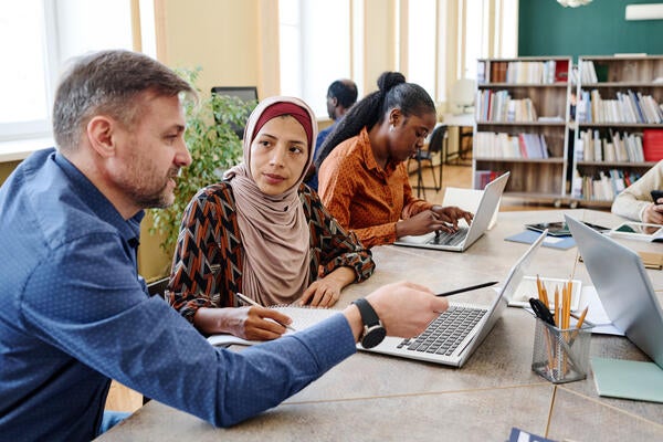 Professional English language teacher helping Muslim student during a lesson