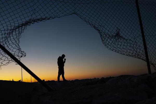 the silhouette of a man surrounded by a fence