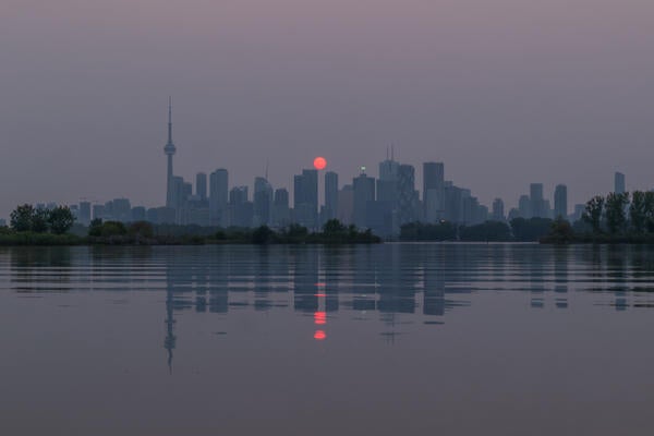 Red sunset over Toronto's skyline caused by wildfire pollution.