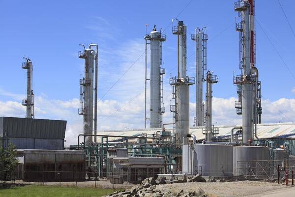 Close up of large gas plant with towers, network of pipes and storage tanks.
