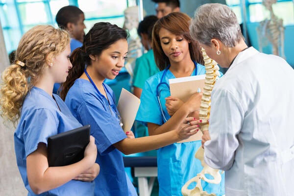 Medical students learning about the human spine with a professor in medical school